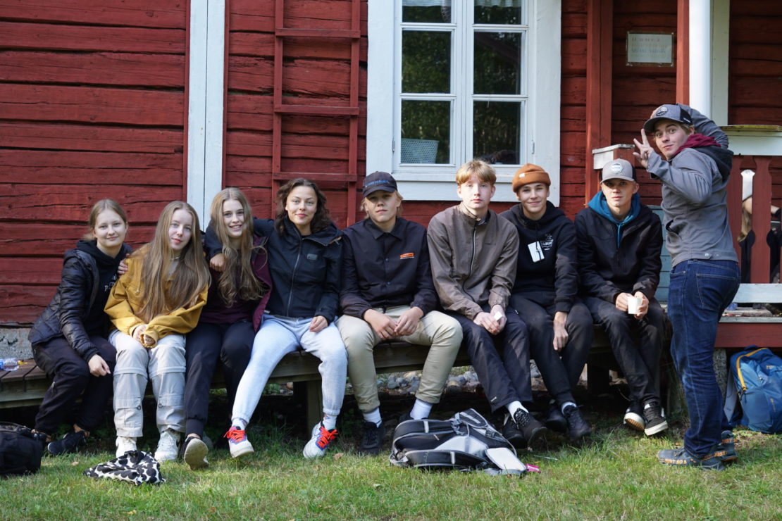 Ryhmä uusia opistolaisia alkuvaelluksen kohteessa, Saarisen leirikeskuksen portailla.